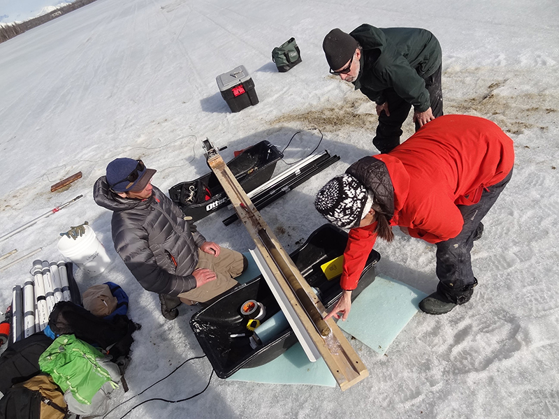 Brad Baxter, Lesleigh Anderson, and Bruce Finney examine a sediment core at April Fools Lake.