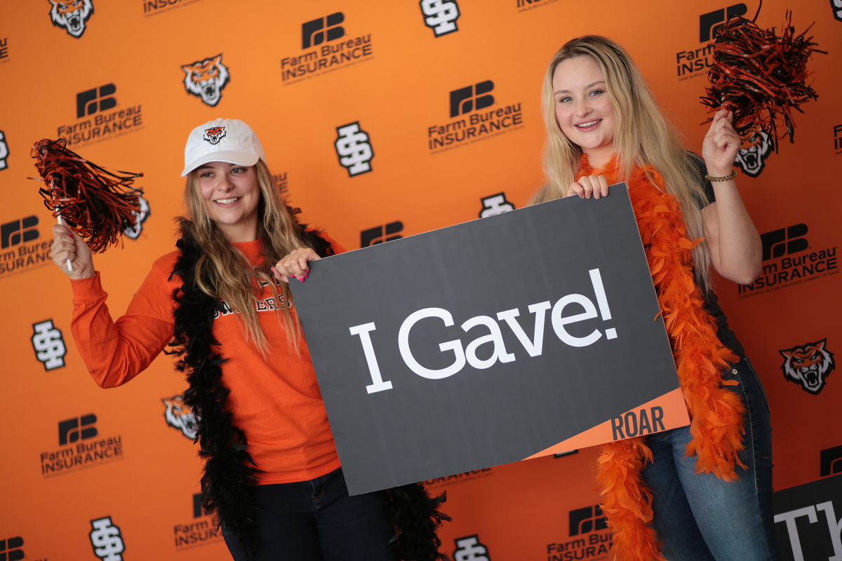 Two donors posing with a sign that says 